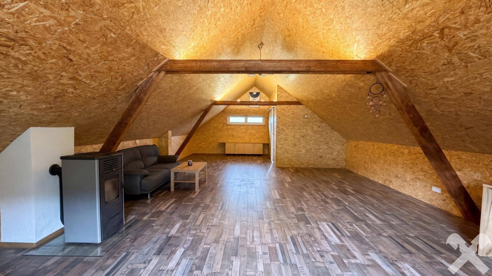Geräumiger, ausgebauter Dachboden mit Holzbalken und einem modernen Ofen.