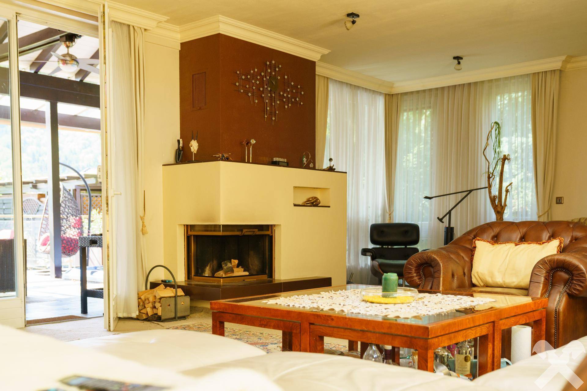 Gemütlicher Kaminbereich im Wohnzimmer mit Ledersessel und Holztisch, bereit für entspannte Abende.
