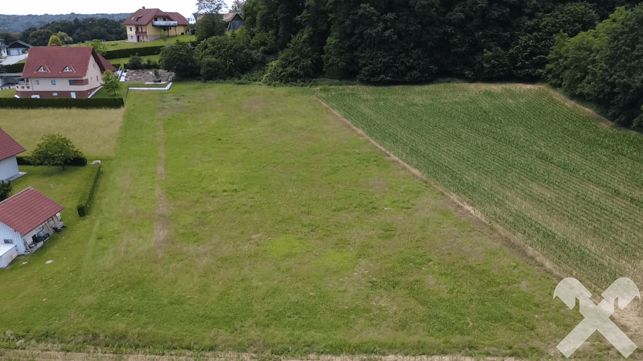 Weitläufiges grünes Grundstück aus der Vogelperspektive mit umliegender Natur und Häusern.