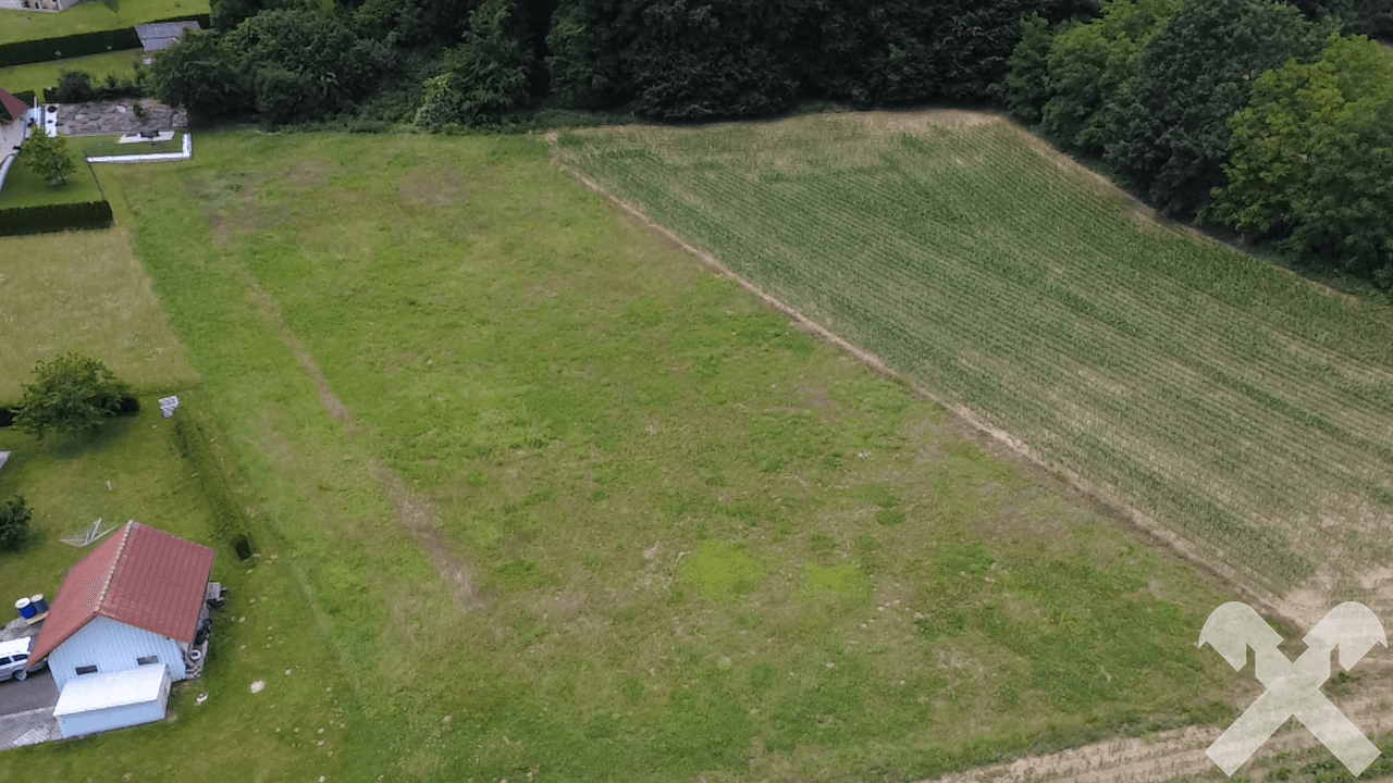 Luftaufnahme eines weitläufigen Grundstücks mit angrenzendem Feld und Wohnbebauung.