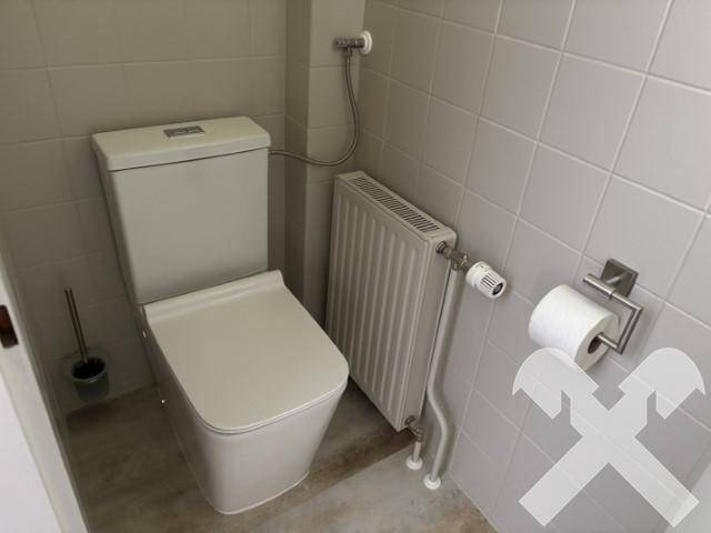 Kleines Gäste-WC mit Toilette und Heizkörper, komplett gefliest.