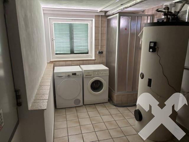 Praktischer Hauswirtschaftsraum im Keller mit Waschmaschine, Trockner und Warmwasserboiler.