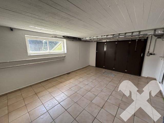 Geräumiger Kellerraum mit Fliesenboden, Fenster und integrierten Schränken für Stauraum.