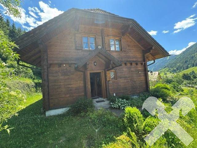 Rustikales Holzhaus mit traditioneller Holzfassade und Eingangsbereich in alpiner Umgebung.