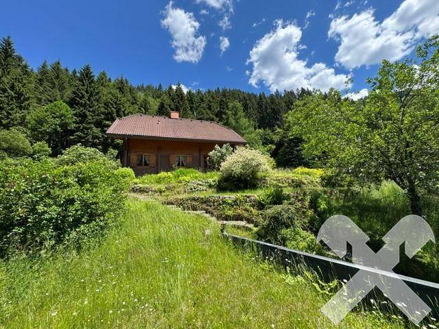 Idyllisches Holzhaus auf einem Hügel mit weitläufigem Garten und Blick auf die umliegende Natur.