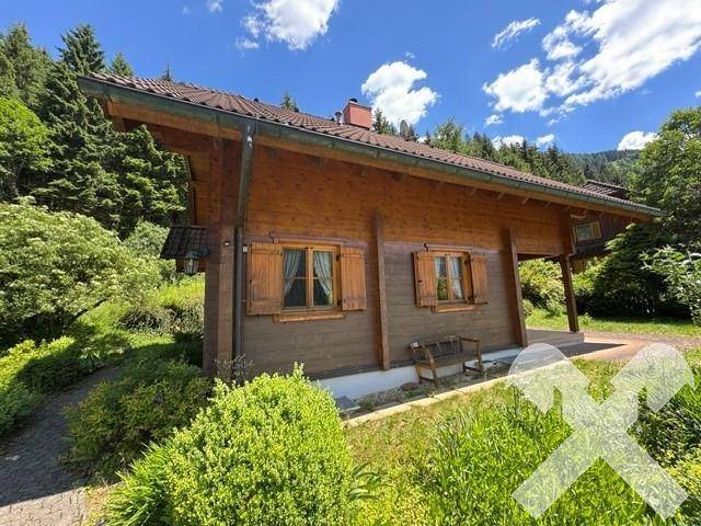 Gemütliches Holzhaus mit Holzfensterläden und einem kleinen Sitzbereich im Freien.