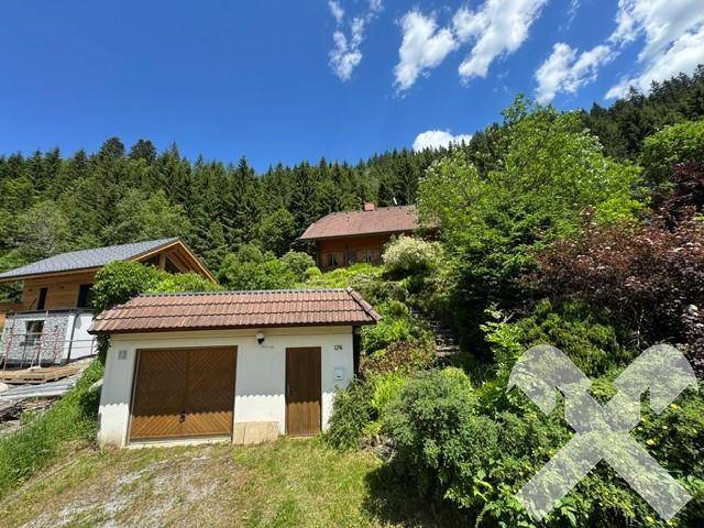 Anwesen mit Haupthaus und separater Garage, umgeben von üppiger Vegetation in den Bergen.