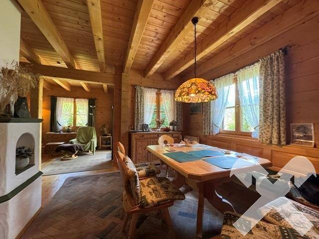 Essbereich mit rustikalem Holztisch, Stühlen und traditioneller Deckenlampe unter Holzbalken.