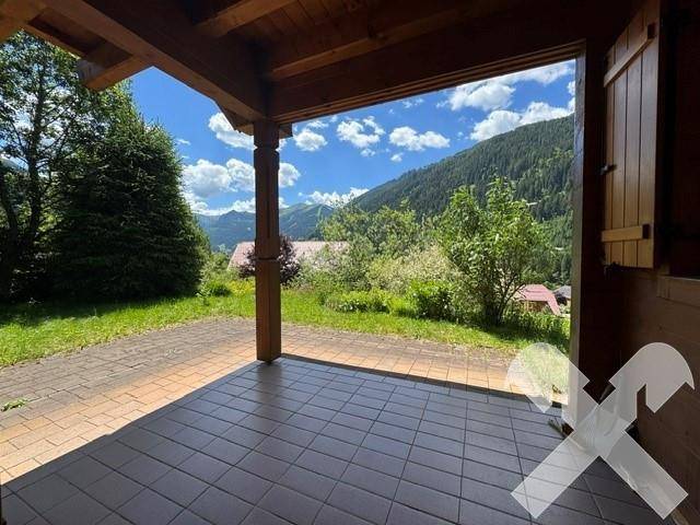 Überdachte Terrasse mit Fliesenboden und herrlichem Blick auf die umliegende Berglandschaft.