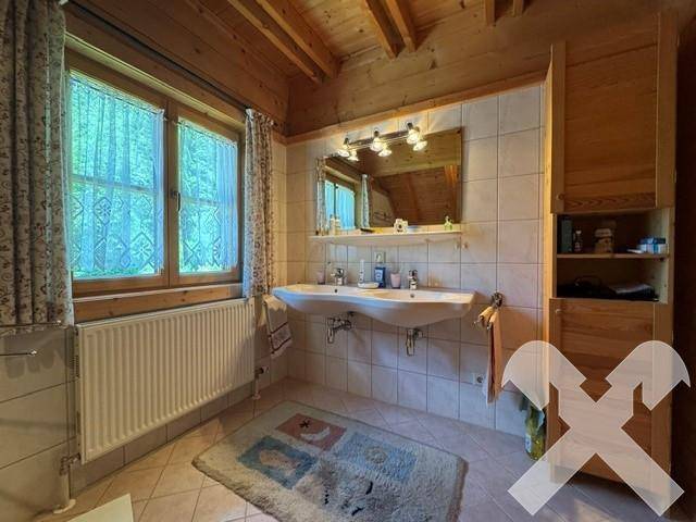 Geräumiges Badezimmer mit Doppelwaschbecken, Fliesenwänden und Fenster für Tageslicht.