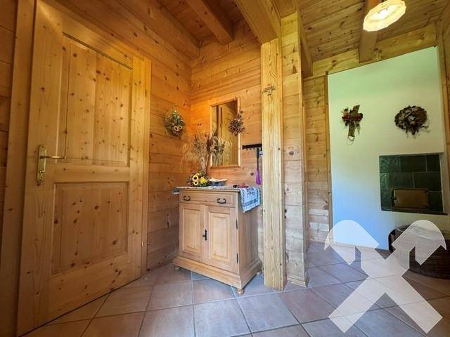 Eingangsbereich mit Fliesenboden, Holzvertäfelung und einem kleinen Schrank mit Spiegel.