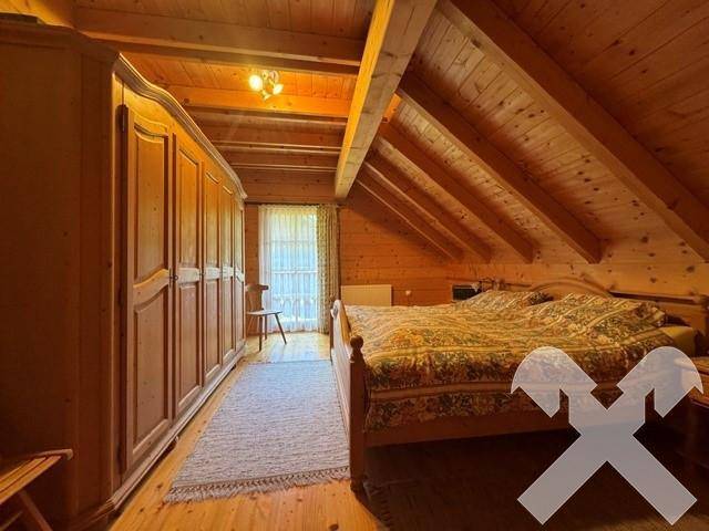 Gemütliches Schlafzimmer im Dachgeschoss mit Holzbalkendecke, Doppelbett und Kleiderschrank.