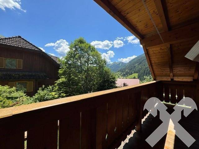 Sonniger Balkon mit Holzgeländer und atemberaubendem Panoramablick auf die Berge.