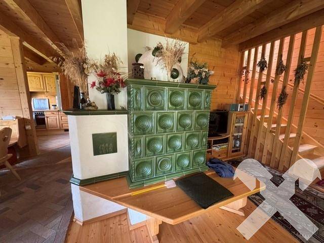 Rustikaler Wohnbereich mit traditionellem Kachelofen, Holzbalkendecke und Holzfußboden.