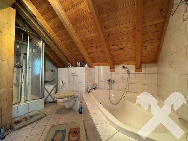 Badezimmer im Dachgeschoss mit Badewanne, Duschkabine und schrägen Decken.