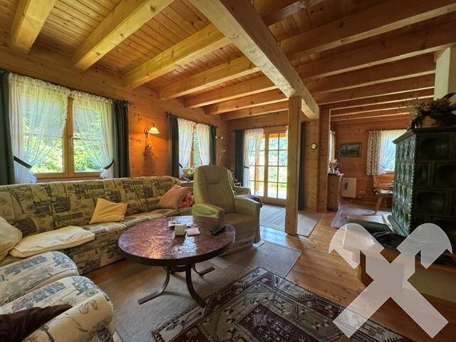 Geräumiges Wohnzimmer mit bequemen Sofas, Holzbalkendecke und Blick in die Natur.