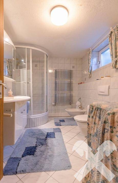 Helles Badezimmer mit Duschkabine, WC, Bidet und beheiztem Handtuchhalter.