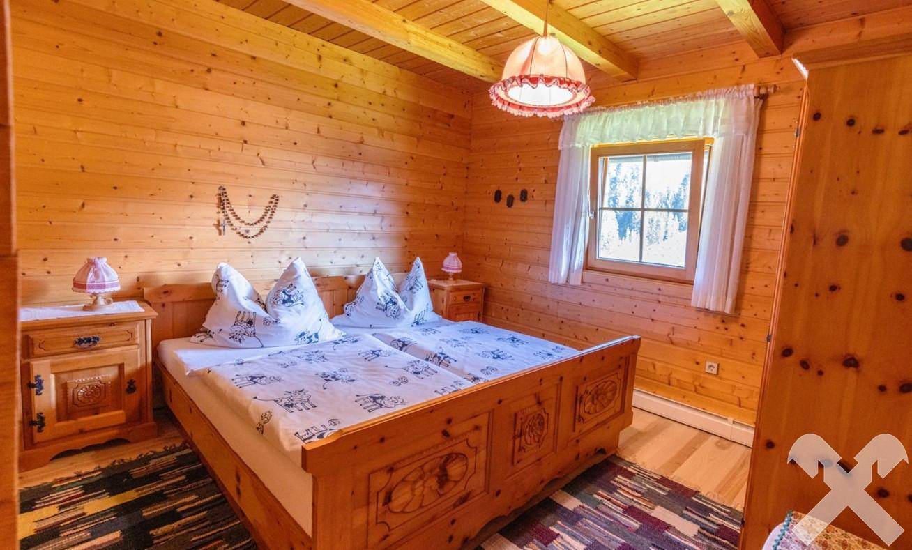 Rustikales Schlafzimmer mit zwei Einzelbetten, Holzwänden und traditioneller Bettwäsche.