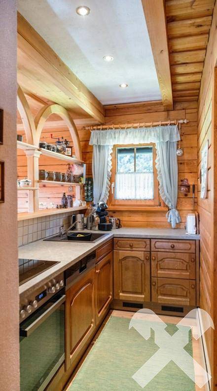 Kleine, funktionale Küche im Landhausstil mit Holzschränken und Fensterblick ins Grüne.