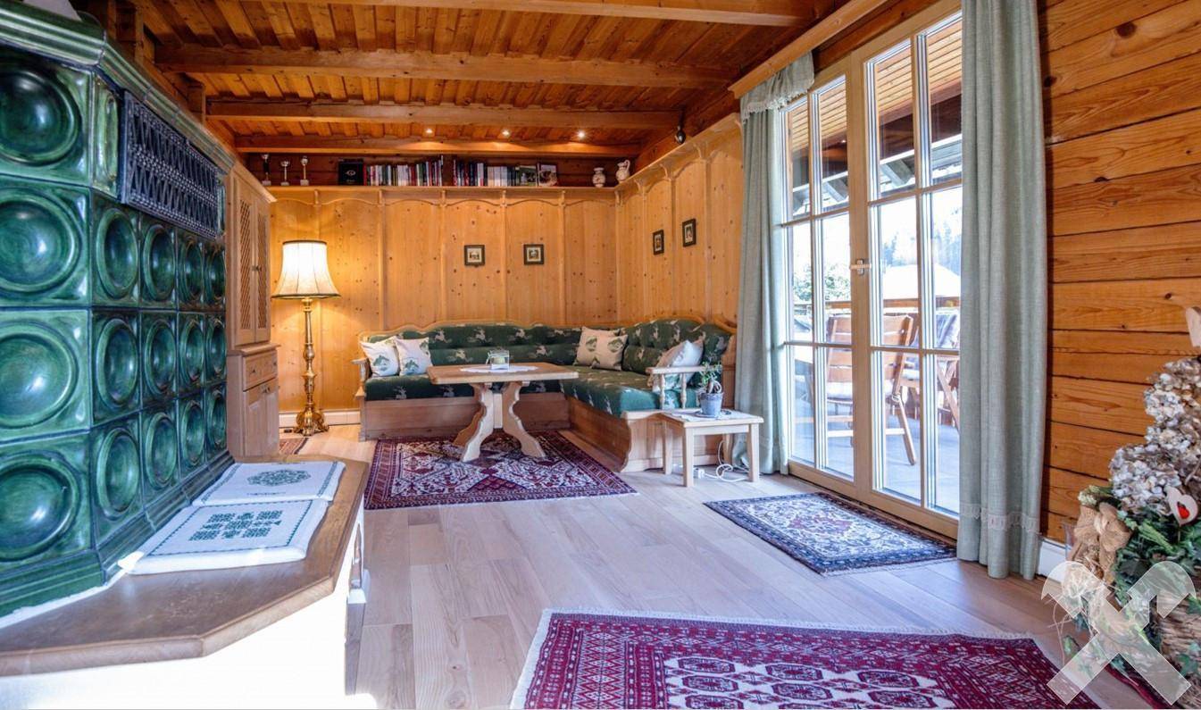 Rustikales Wohnzimmer mit Holzbalkendecke, gemütlicher Sitzecke und Zugang zur Terrasse.