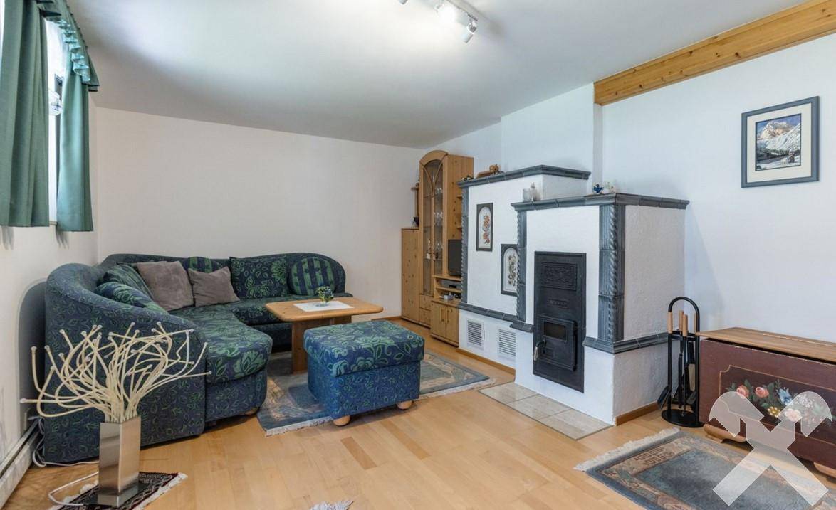 Gemütliches Wohnzimmer mit Sofa, Kachelofen und traditioneller Einrichtung.