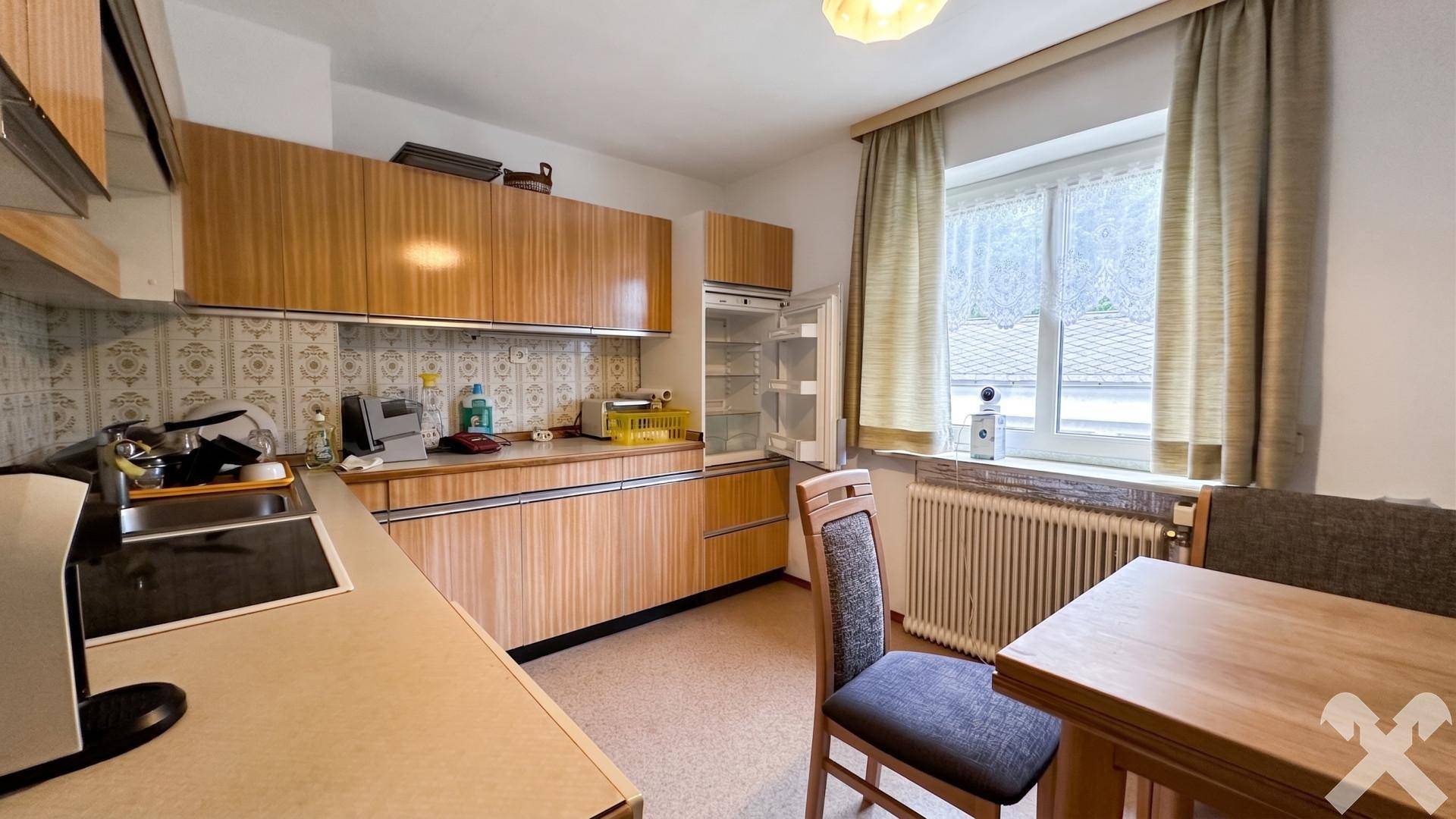 Küche mit Holzschränken, Esstisch und Fenster mit Blick auf die Umgebung.