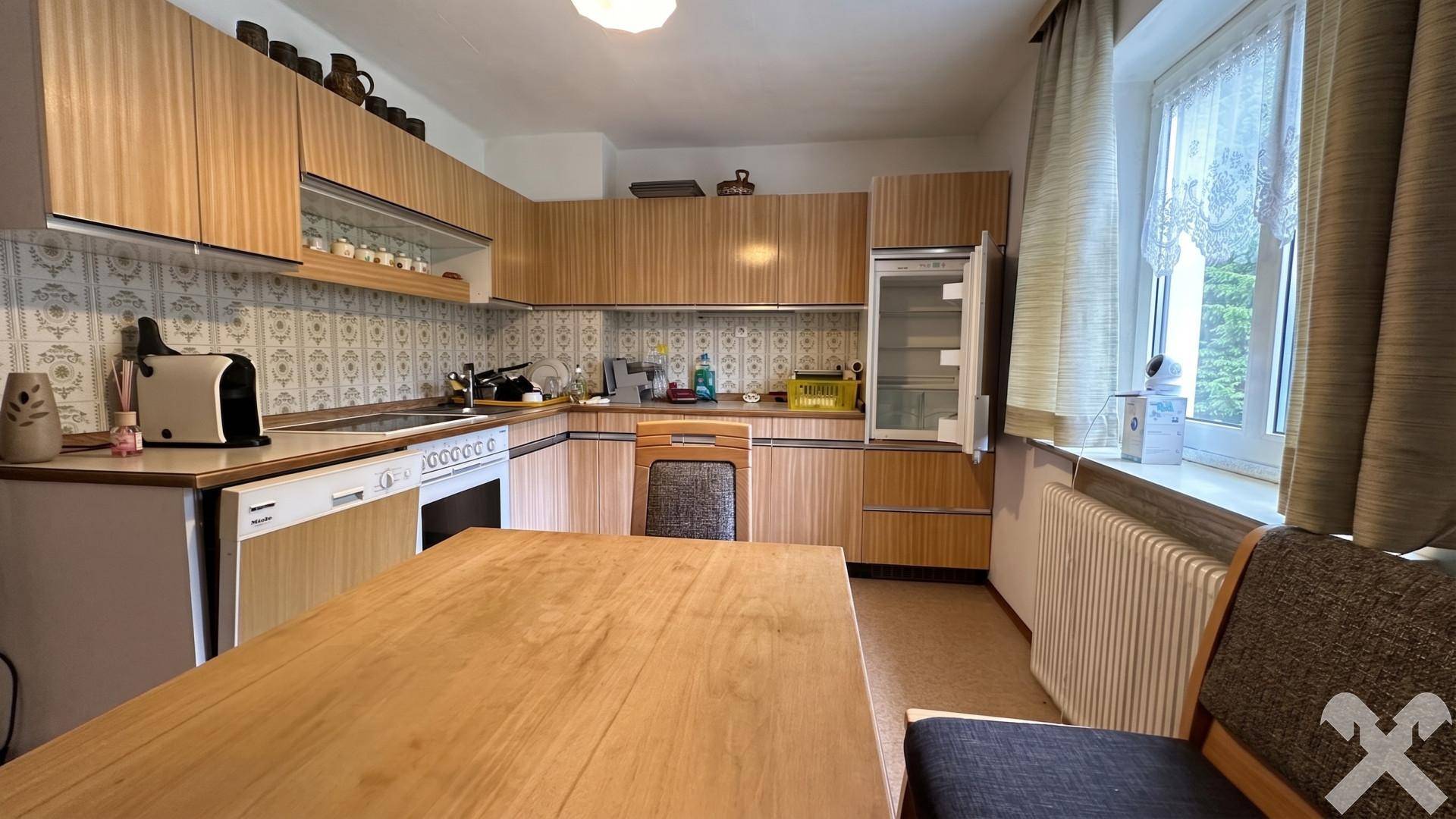 Gemütliche Wohnküche mit Holzmöbeln, integrierten Geräten und ausreichend Platz für einen Esstisch.
