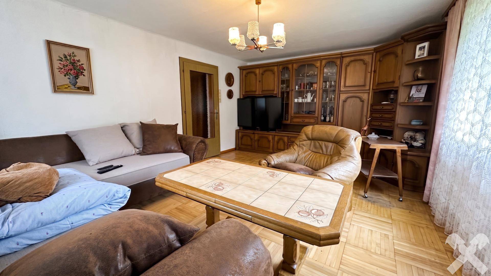 Wohnzimmer mit klassischem Parkettboden und großer Holzschrankwand für Stauraum.