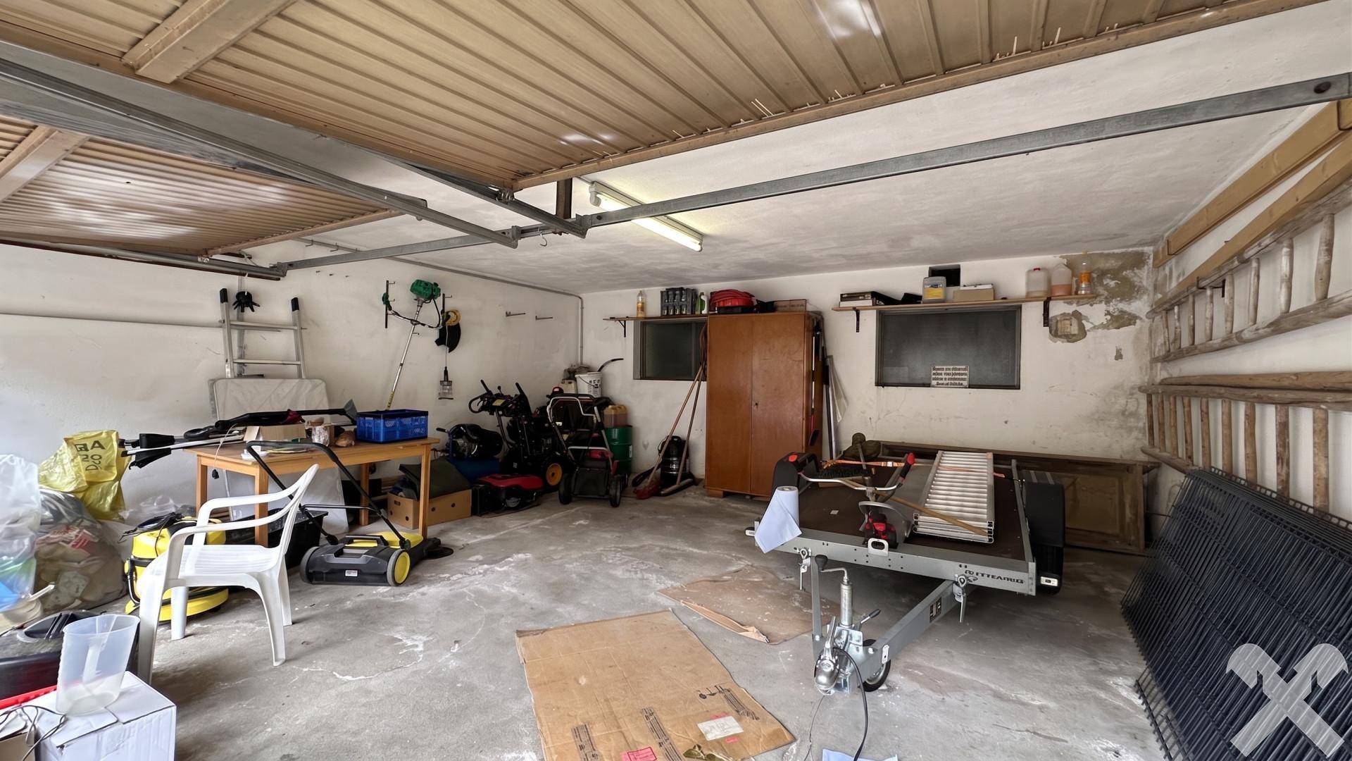 Innenansicht der Garage mit viel Stauraum für Fahrzeuge und Werkzeuge.