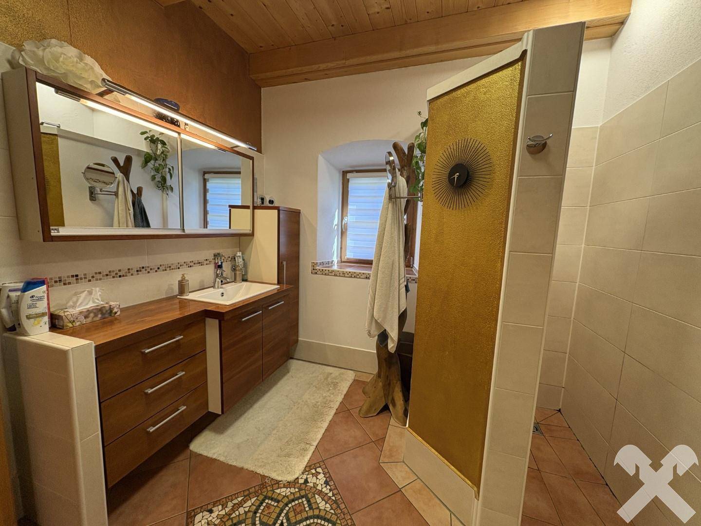 Badezimmer mit Holzwaschtisch, Spiegelschrank und einer geräumigen begehbaren Dusche.