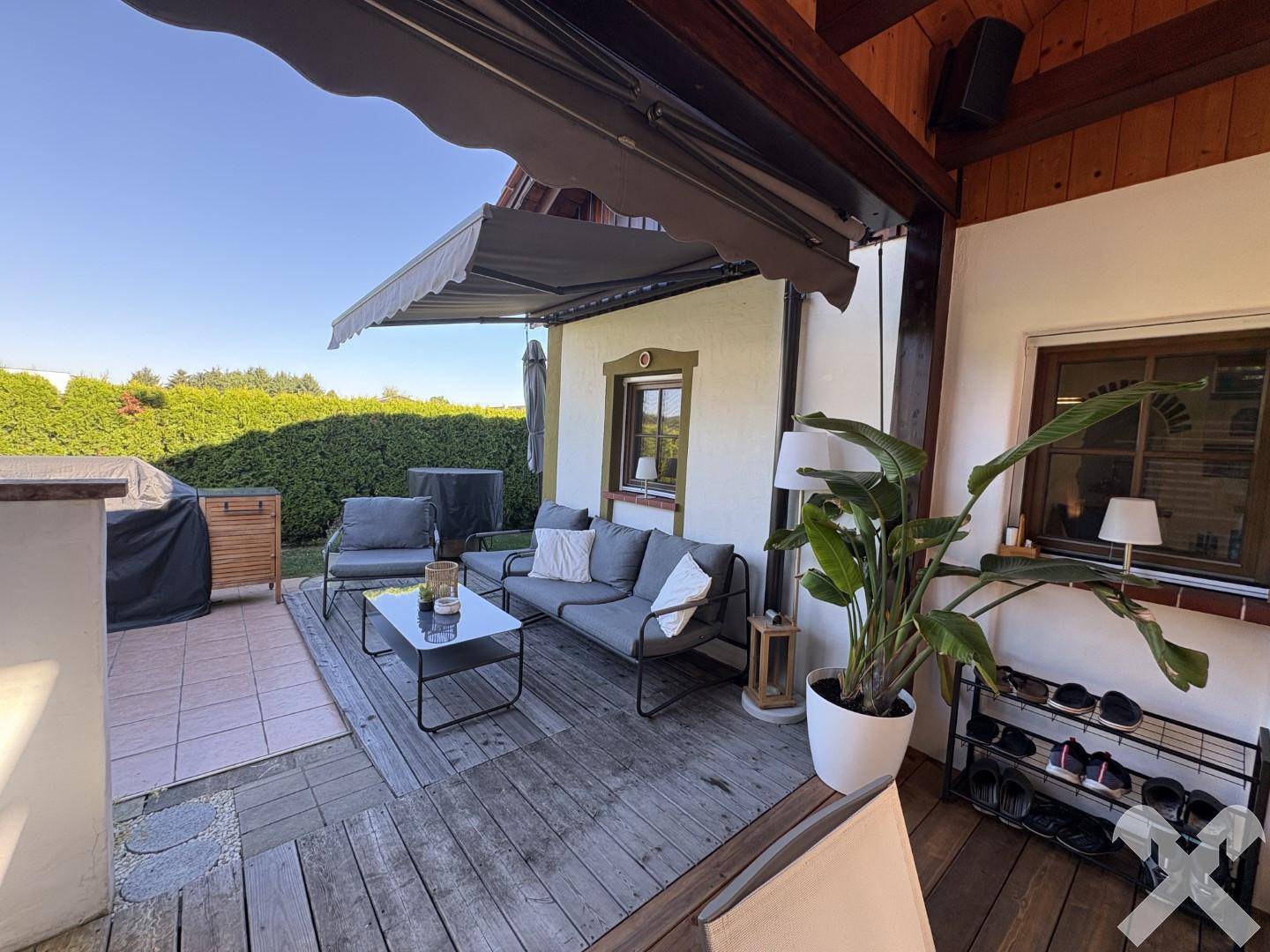 Geräumige Terrasse mit bequemen Gartenmöbeln, Markise und Blick auf den gepflegten Garten.