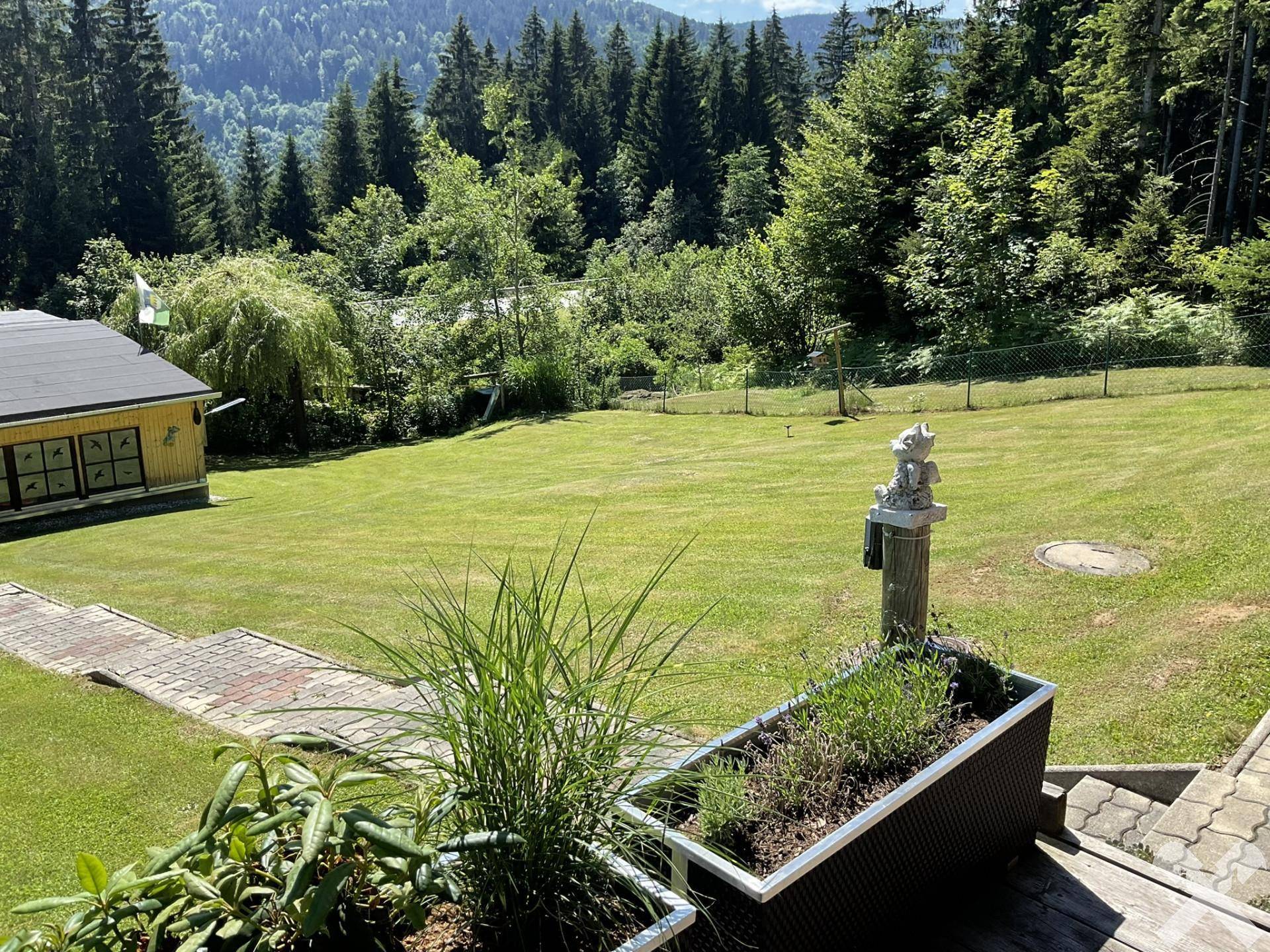 Weitläufiger Garten mit Blick auf die umliegenden Wälder und Berge in der Ferne.