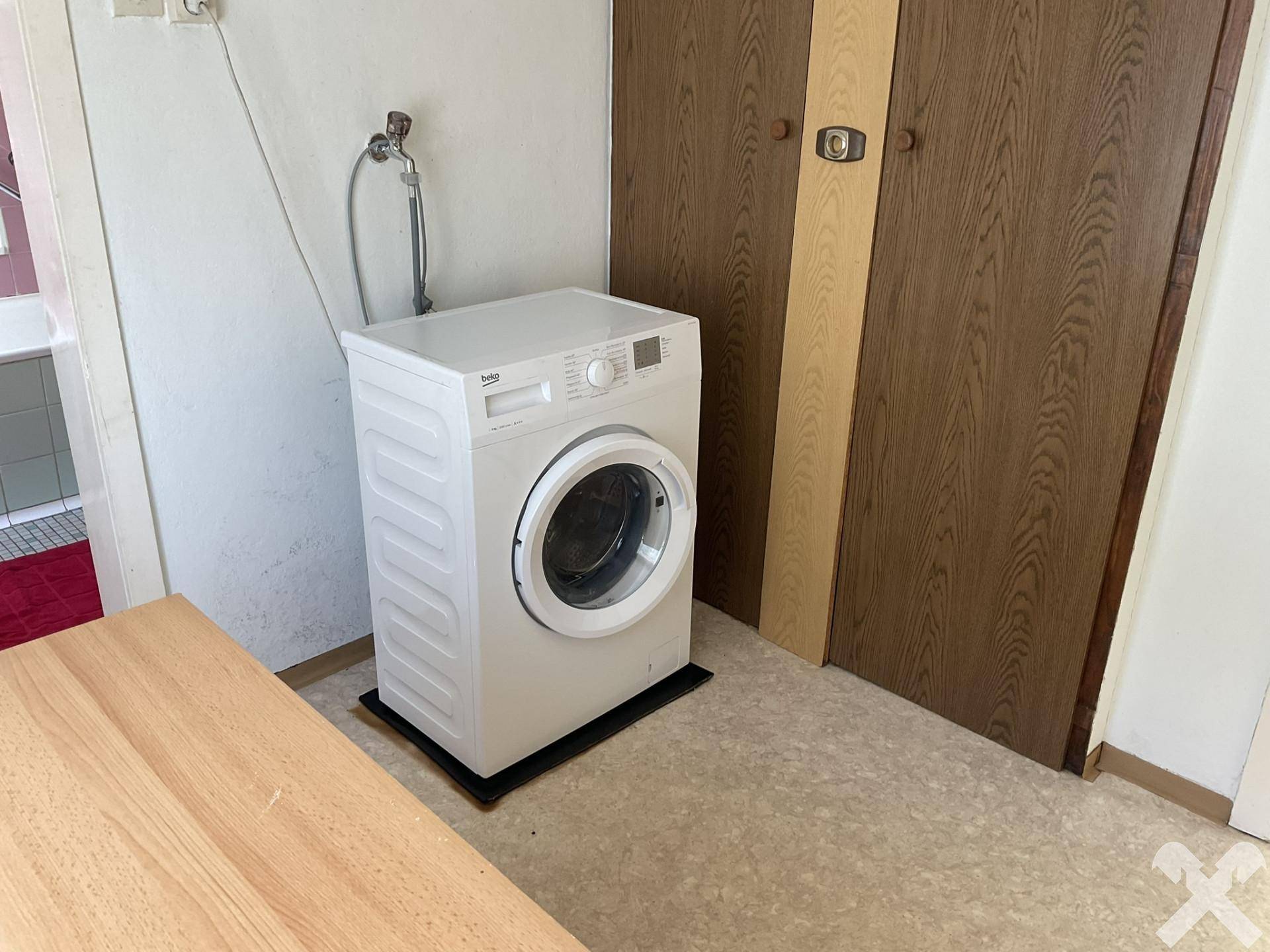 Hauswirtschaftsraum mit einer Waschmaschine und Holztüren.