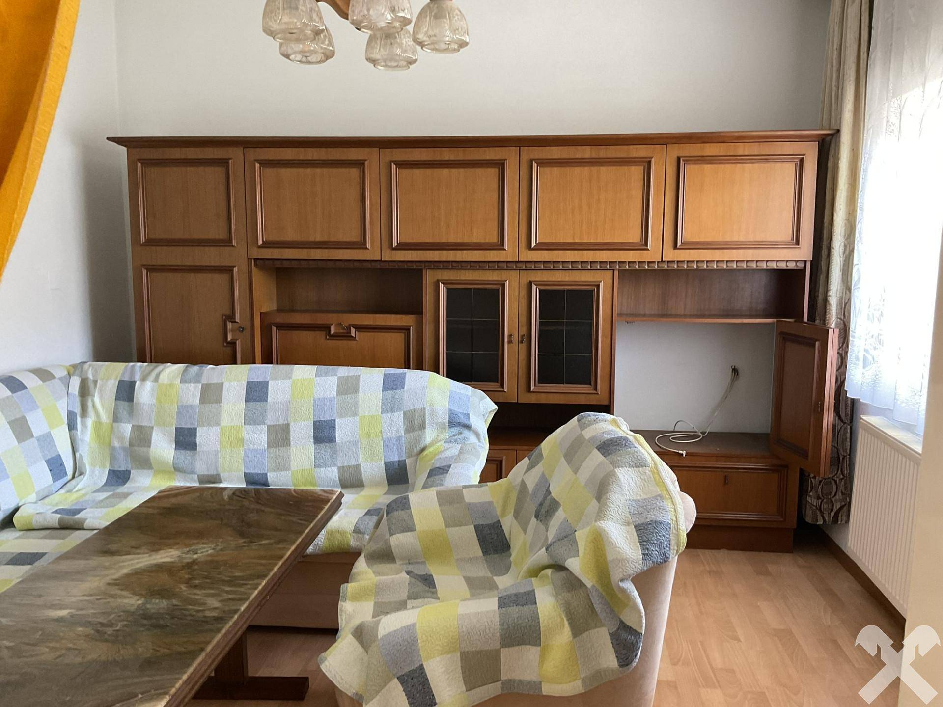 Gemütliches Wohnzimmer mit einer großen Holzschrankwand, Sofa und einem Couchtisch.