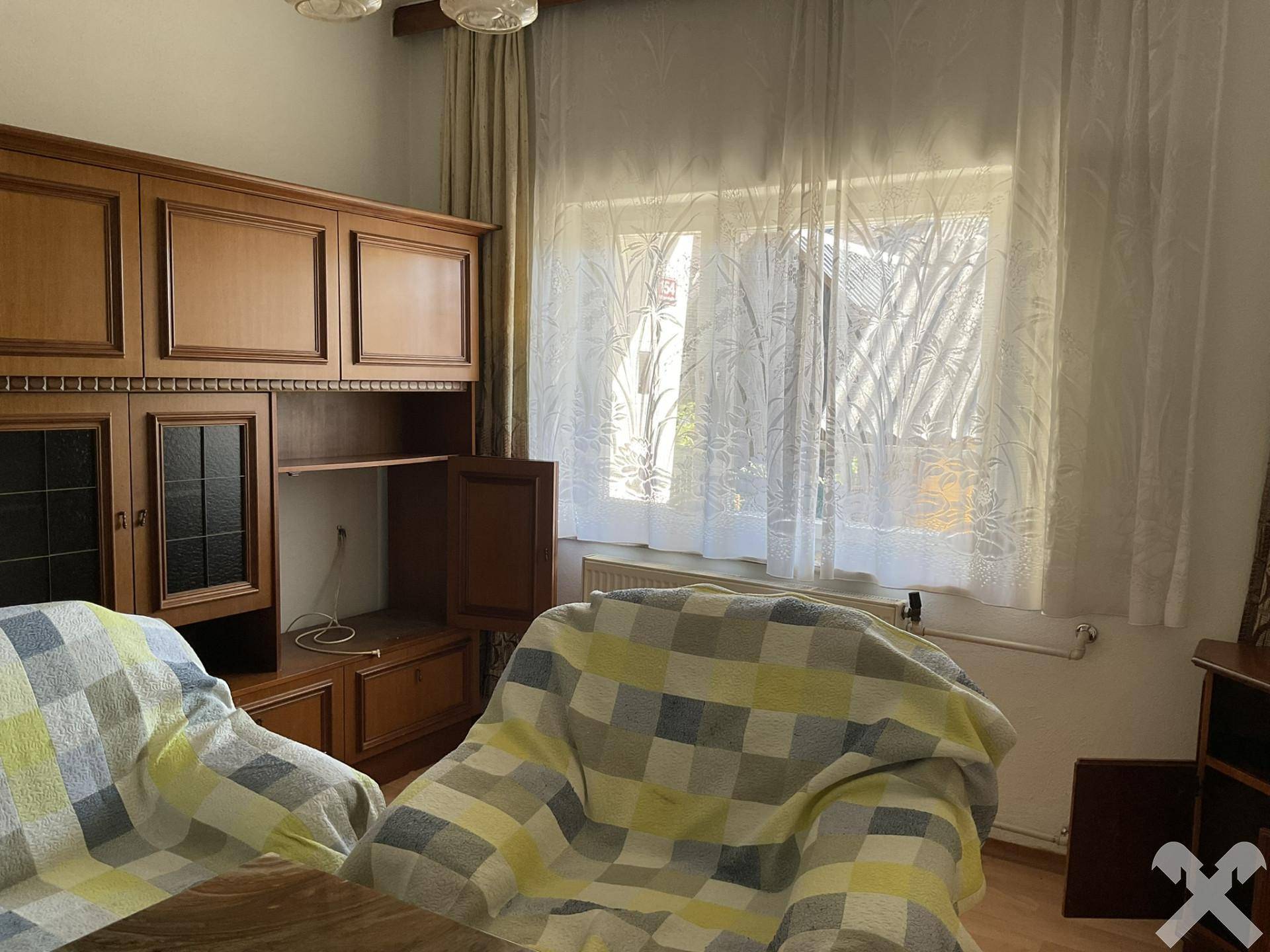 Wohnzimmer mit Fenster, das viel Tageslicht hereinlässt, und einem Sessel mit karierter Decke.