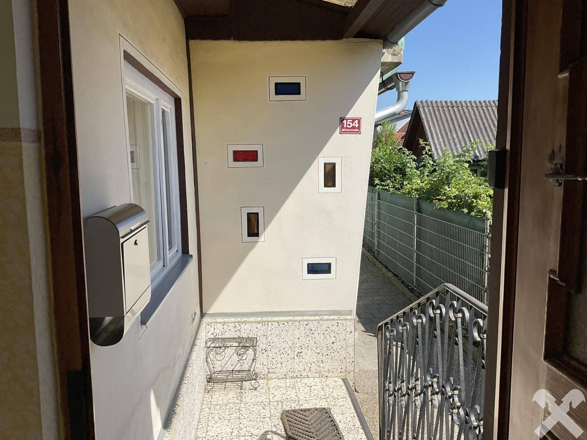 Blick vom Eingang auf den kleinen gepflasterten Bereich vor dem Haus mit dekorativen Elementen.
