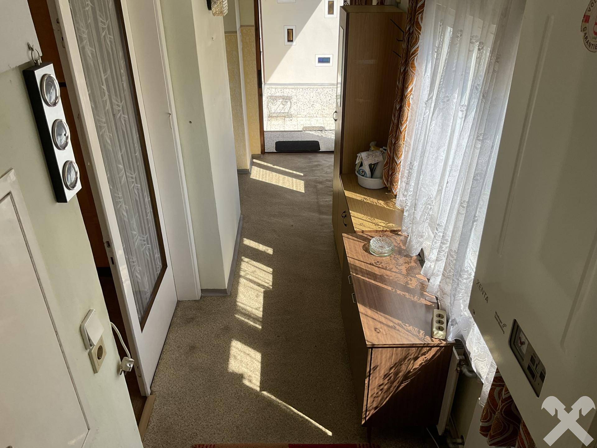 Heller Eingangsbereich mit Teppichboden und Sonnenlicht, das durch die Tür fällt.