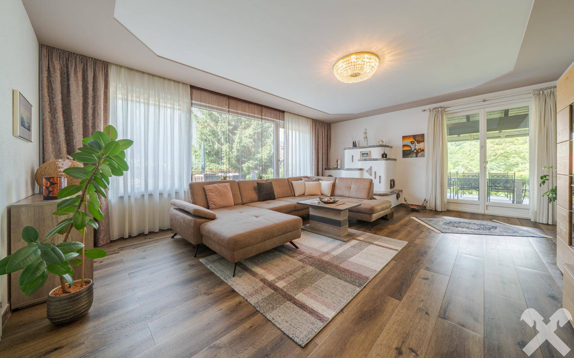 Gemütliches Wohnzimmer mit Holzboden, großem Ecksofa und Zugang zu einem Balkon mit Bergblick.