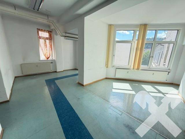 Großer, heller Bürobereich mit Betonboden, großen Fenstern und viel Tageslicht.