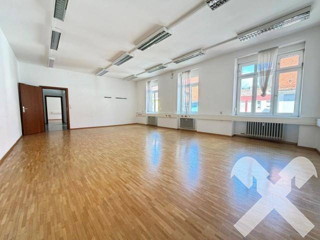 Geräumiger Büroraum mit Fischgrätparkett, großen Fenstern und viel Tageslicht.