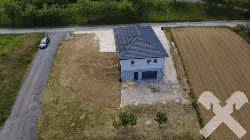 Neubau-Einfamilienhaus mit Doppelgarage, Photovoltaikanlage und angrenzendem Feld.