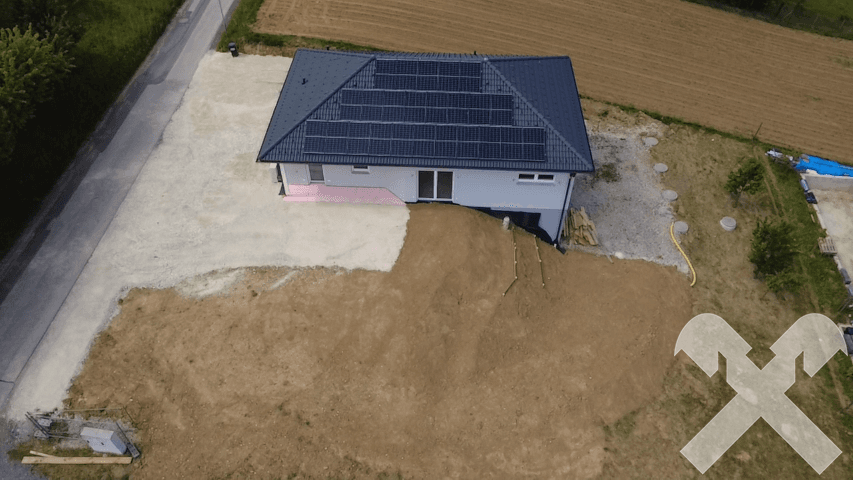 Neubau-Einfamilienhaus in der Bauphase mit vorbereitetem Grundstück und Photovoltaikanlage.