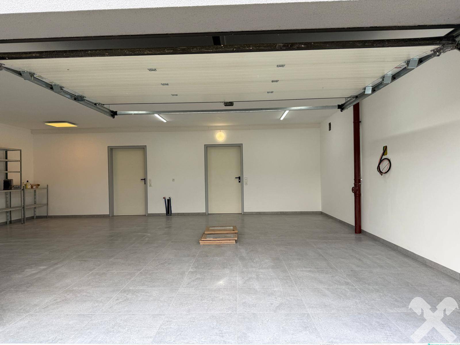 Geräumige Doppelgarage mit Fliesenboden und Zugangstüren, bereit zur Nutzung.
