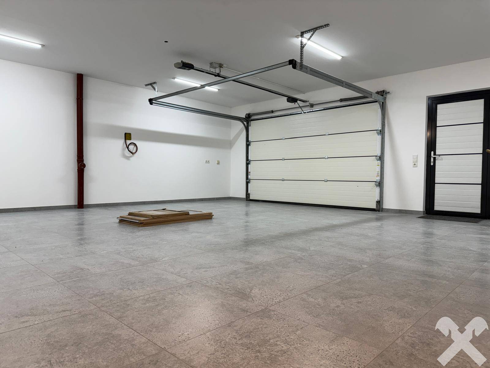 Große Garage mit automatischem Tor und Fliesenboden, bietet viel Platz.