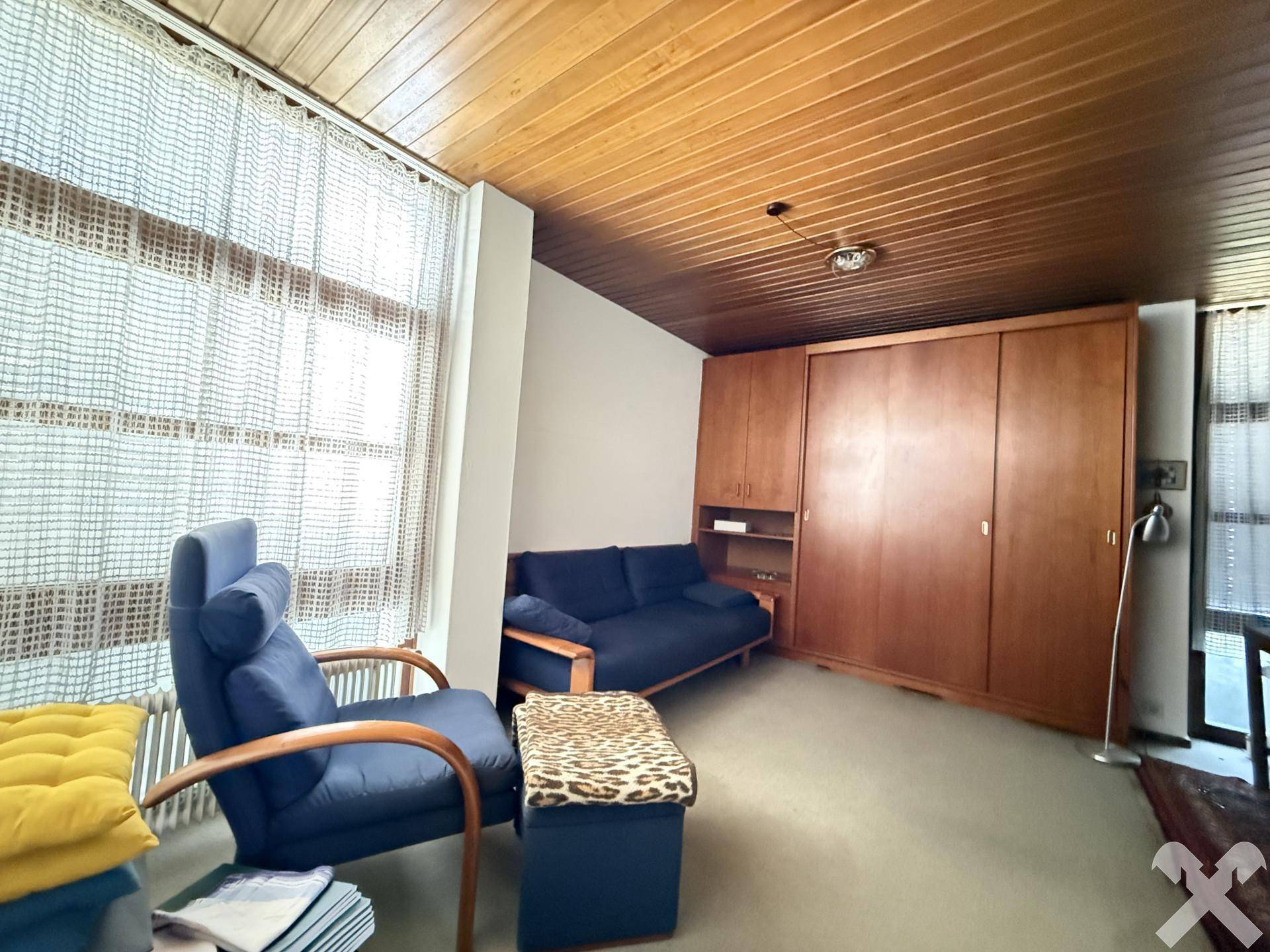 Gemütliches Schlafzimmer mit Sofa, Holzdecke und praktischen Einbauschränken für Stauraum.