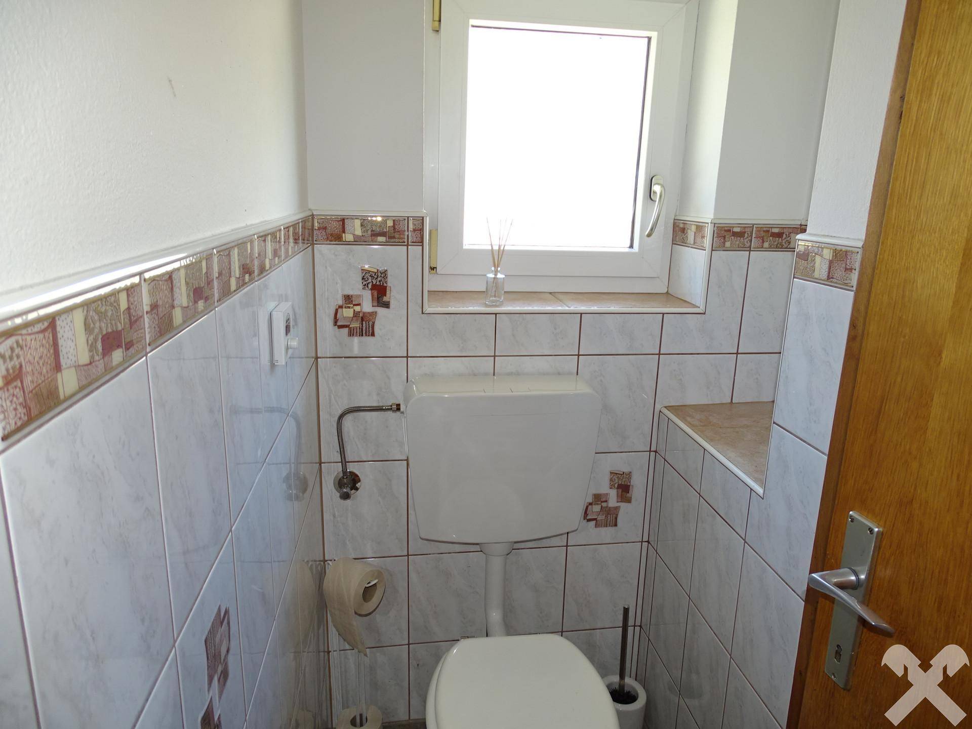 Kleines Gäste-WC mit Fenster, weißen Fliesen und dekorativen Bordüren.