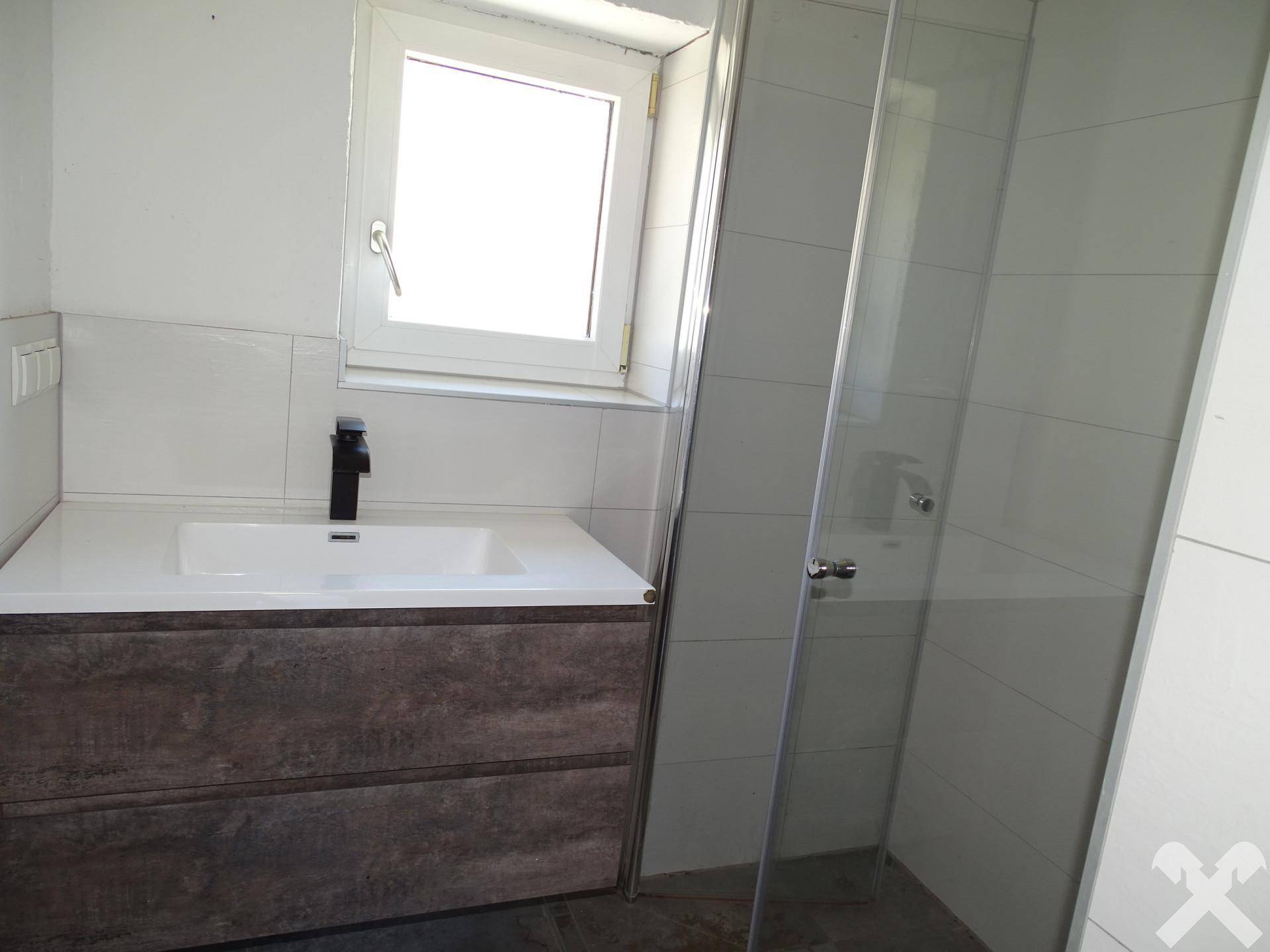 Modernes Badezimmer mit Waschtisch, Spiegel und einer Duschkabine mit Glaswand.
