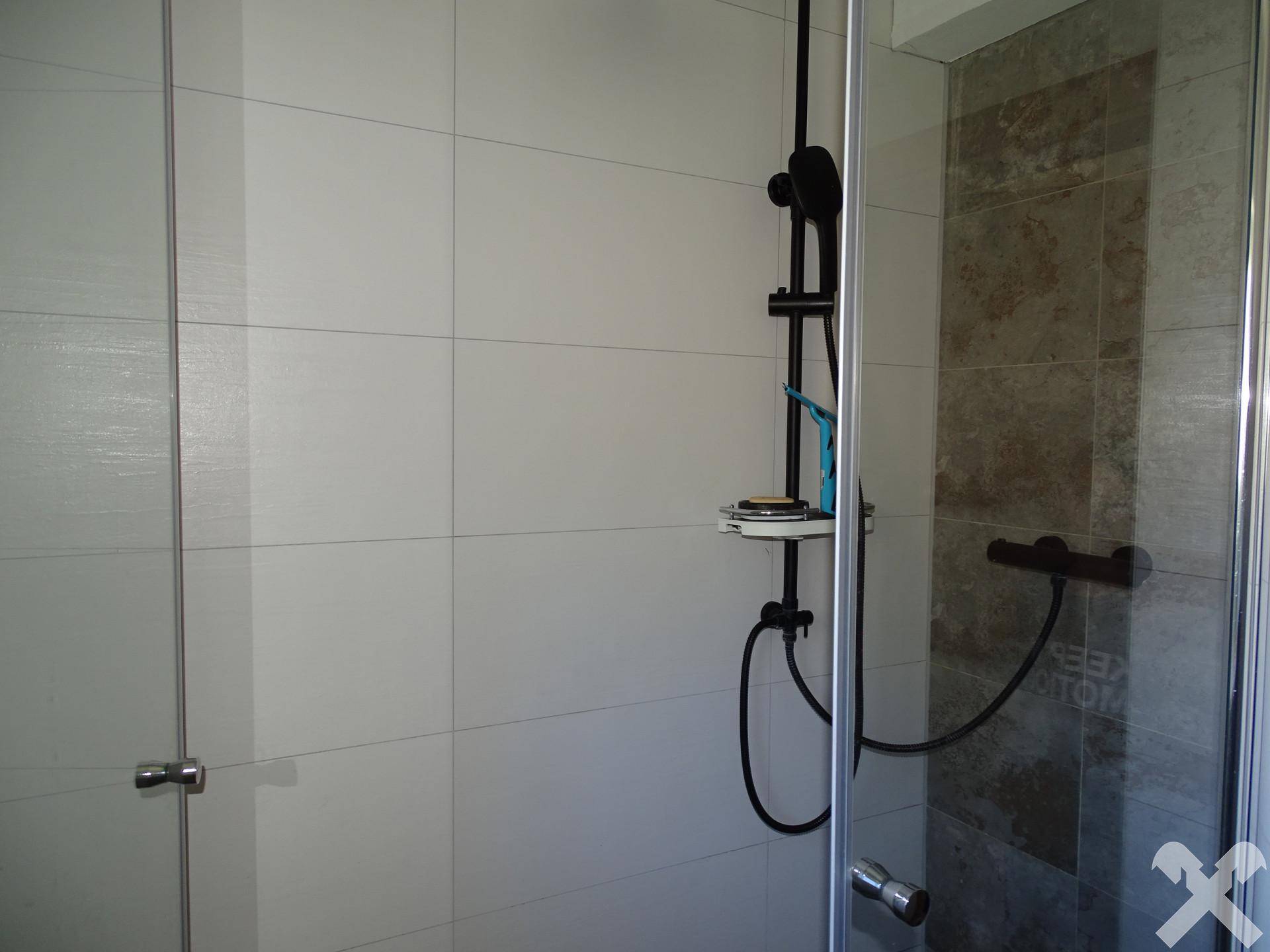 Duschbereich im Badezimmer mit modernen Fliesen und einer schwarzen Duscharmatur.