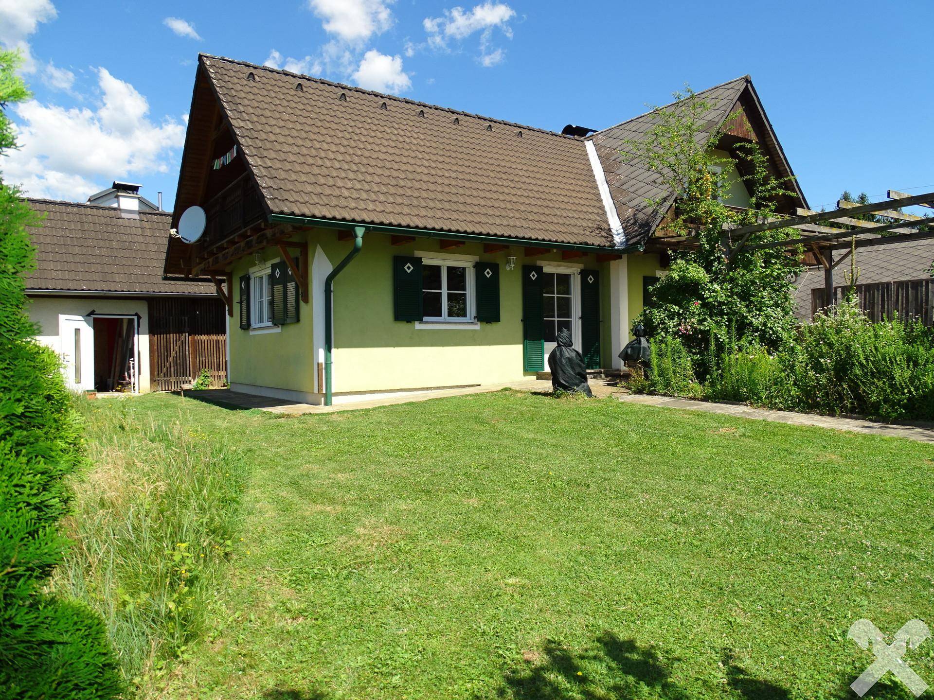 Ansicht des Hauses von der Rasenfläche aus, umgeben von gepflegtem Grün und Sträuchern.