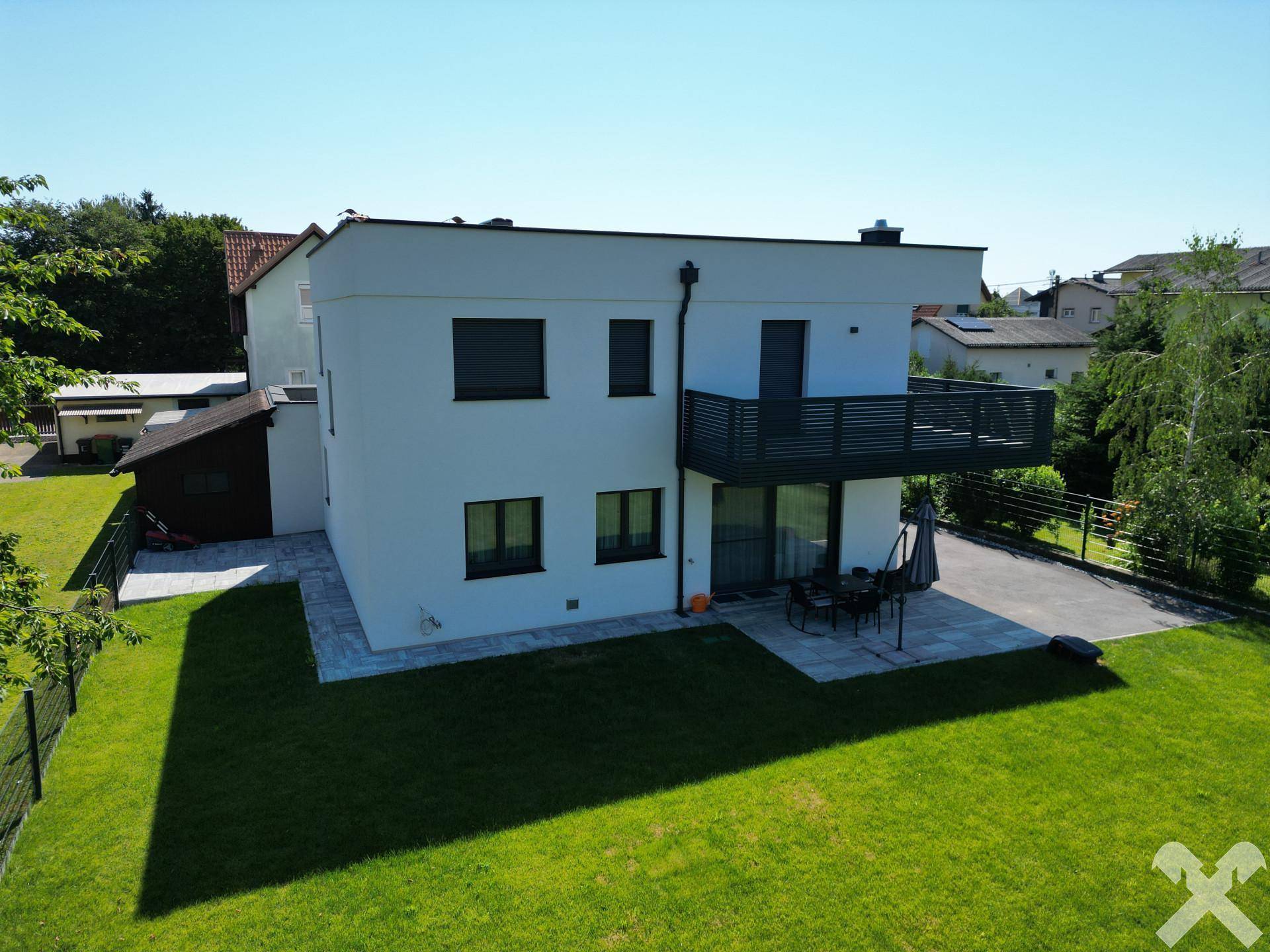 Vogelperspektive des modernen Hauses mit großem Garten, Terrasse und Balkon an einem sonnigen Tag.